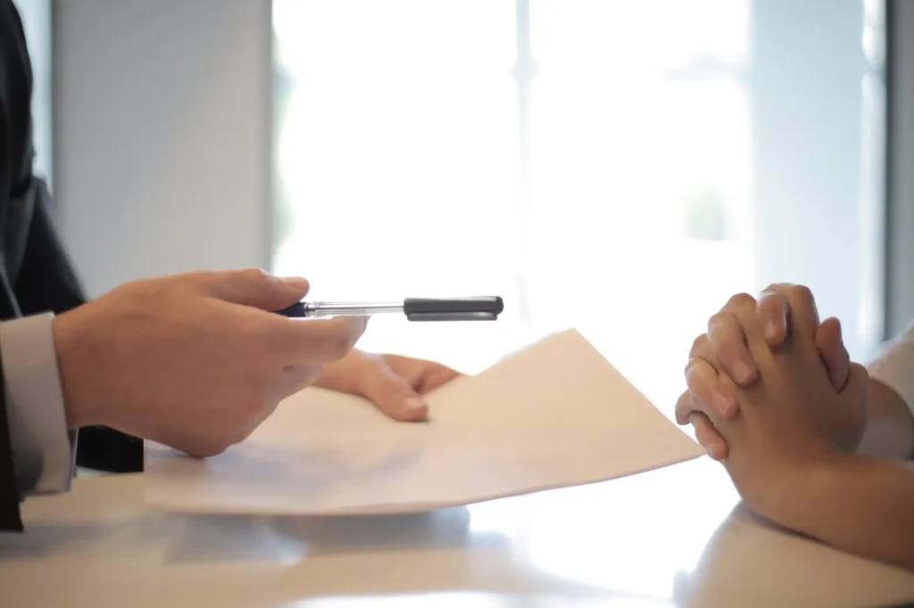Two professionals shaking hands over a signed document